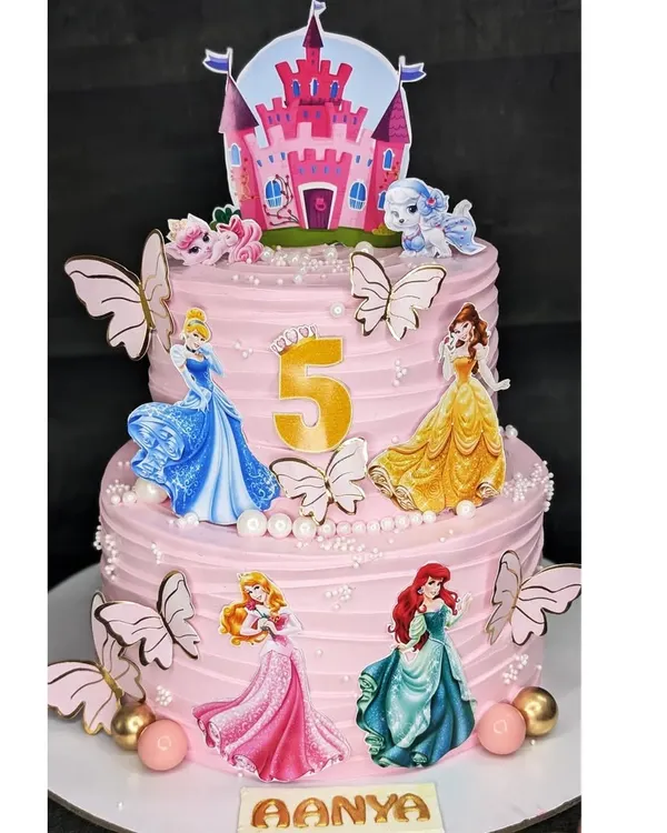 A two-tier Disney Princess dream cake for a 5th birthday. This eggless black forest cake is decorated with multiple princesses, butterflies, and a castle topper for a truly royal celebration.