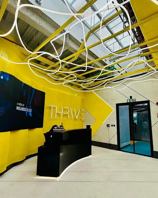 The reception of the 8,000 sq ft DLF Thrive Gym in Chennai. The vibrant yellow accents pay homage to the city's spirit, while the custom 'noodle' light fixture adds a unique, energetic touch to the entrance.
