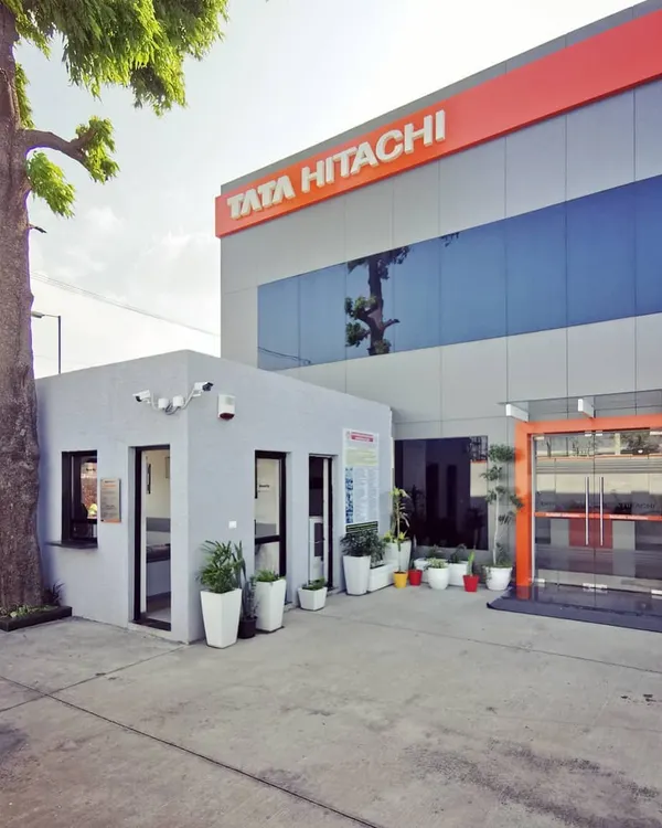 The main entrance of the award-winning Tata Hitachi dealership. The design combines a professional gray facade with the brand's signature orange, creating a welcoming yet authoritative presence that reflects the company's identity.