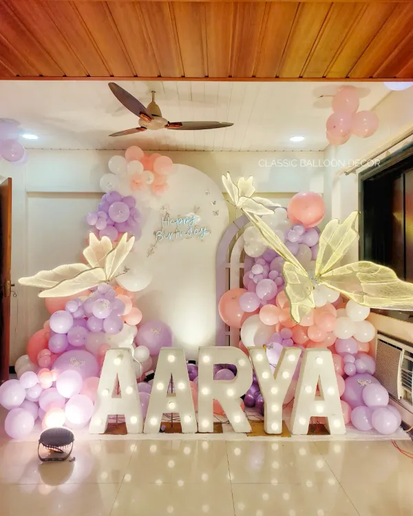 A stunning butterfly theme for a first birthday, featuring large marquee letters, pastel balloons, and oversized, elegant butterfly wings.