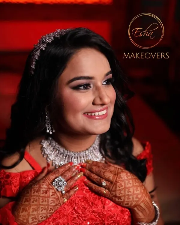 A stunning bride ready for her reception in a sparkling red gown. The makeup is pure glamour, with soft smokey eyes, radiant skin, and a beautiful diamond hair accessory.