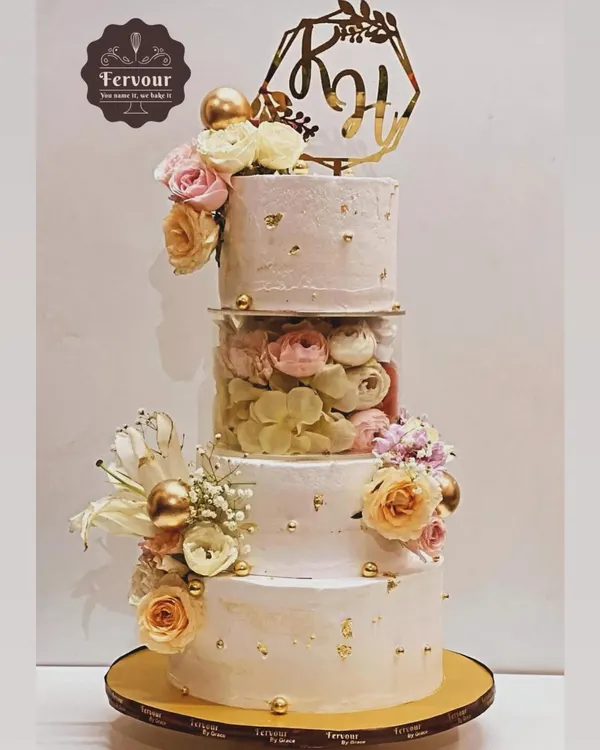 A stunning floral cake perfect for a wedding or grand engagement. This design features three tiers with a transparent separator filled with fresh flowers, combining modern structure with classic romantic style. The flavours were a mix of chocolate mousse and salted caramel.