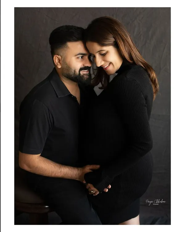 An intimate moment between partners, captured in a classic studio setting. The focus on simple, dark tones allows the emotion and connection to be the true highlight of the portrait.