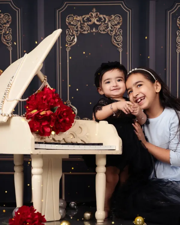 Sisters making music together. A sweet moment between an older and younger sister at our miniature piano.