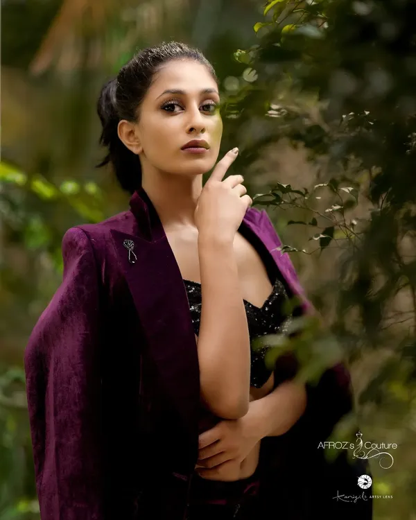 A model wearing a custom purple velvet two-piece set. This outfit includes a sequined bralette, high-waisted pants, and a matching velvet jacket, creating a luxurious and edgy look.