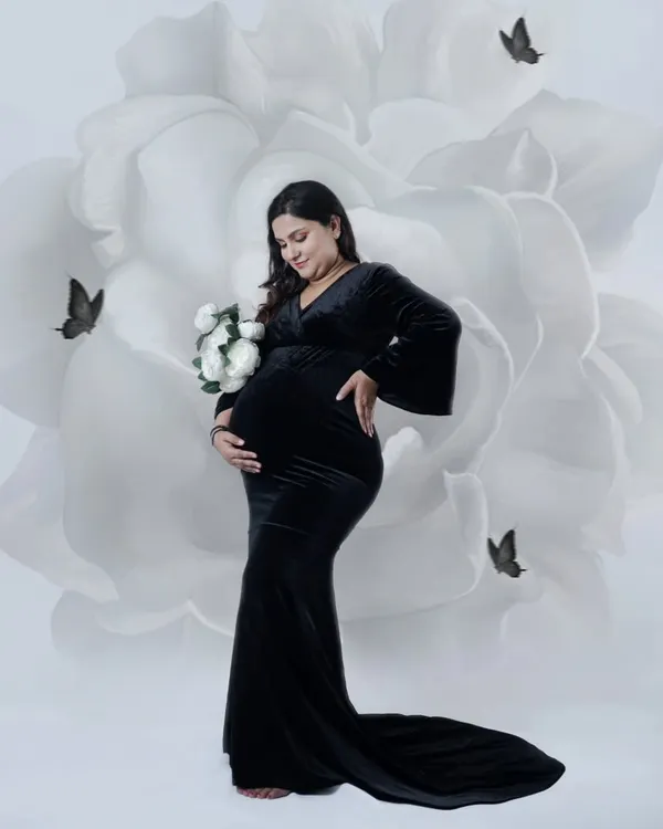 A striking portrait of a mother-to-be in a classic black gown. We used a digital backdrop of a large white flower to create a modern and artistic look.