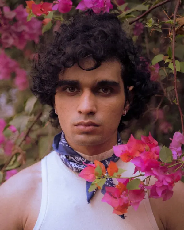 A creative outdoor portrait using flowers in the foreground to frame the subject's face. This technique adds depth and a unique artistic touch to a standard headshot.