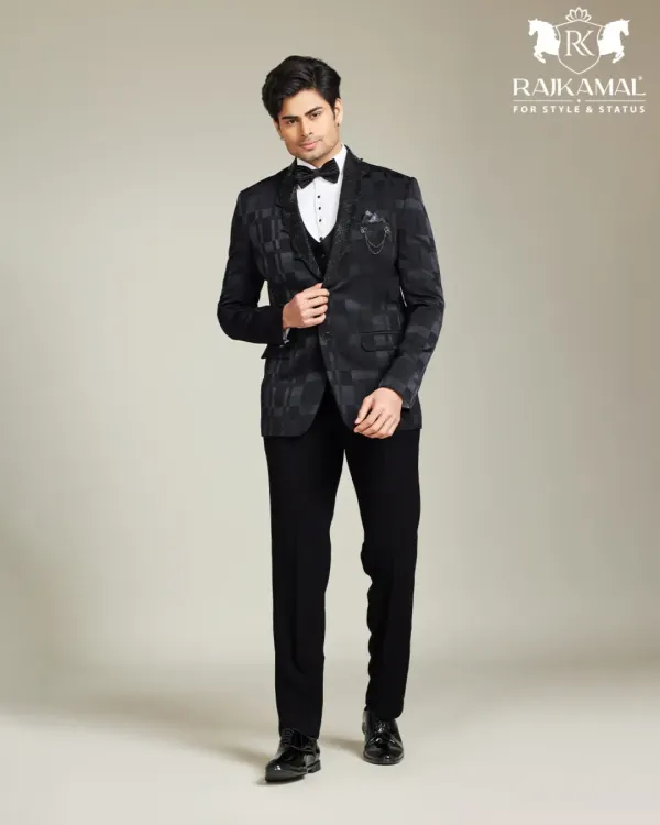 A model looking sharp and iconic in a modern black tuxedo. The jacket features a subtle, tone-on-tone pattern, perfect for the man who appreciates premium, understated style.