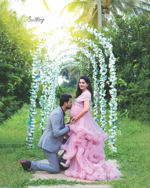 A fairytale moment in my private garden. The husband-to-be kneels to kiss the baby bump under a beautiful floral arch, creating a romantic and unforgettable memory.