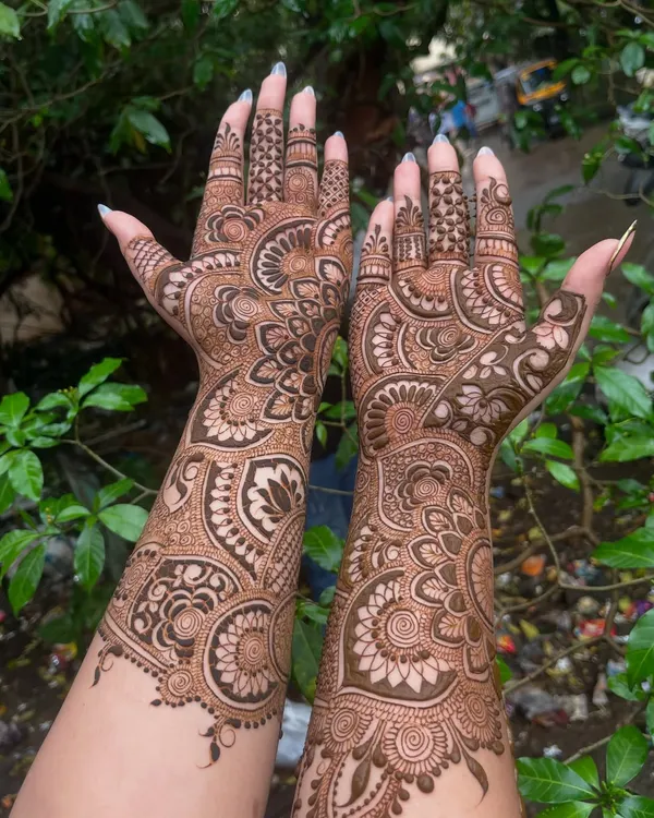 A stunning example of full coverage bridal mehandi. This design features large, intricate mandalas and paisley patterns that flow from the fingertips all the way up the arms.