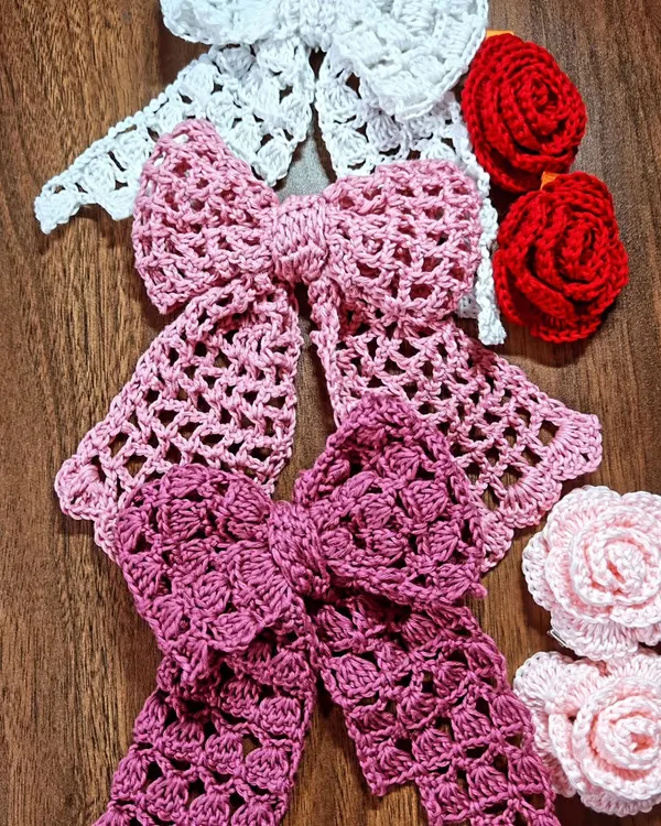 A beautiful collection of my handmade crochet hair accessories. This set includes large, elegant bows in different shades of pink and white, alongside red and pink rose hair clips.
