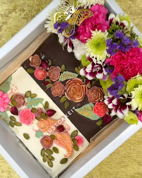 This 'Bloom with Gratitude' hamper features two artisanal chocolate bars, one white and one dark, both hand-painted with edible floral designs. It's paired with a bouquet of fresh, exotic flowers.