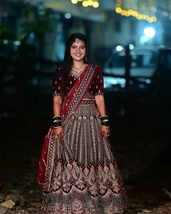 This bride is glowing for her reception. The deep red velvet lehenga is complemented by a soft glam makeup look and an elegant hairstyle, perfect for an evening celebration.