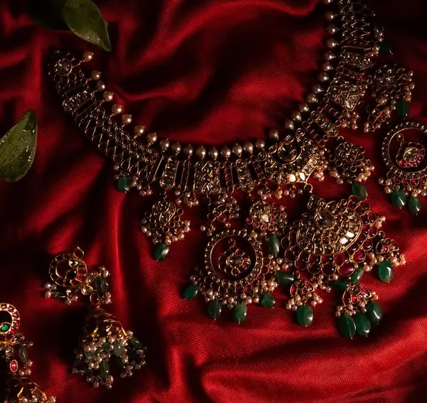 A close-up of the stunning temple jewelry, laid out on rich red silk. This detailed shot highlights the craftsmanship and beauty of the traditional bridal accessories.