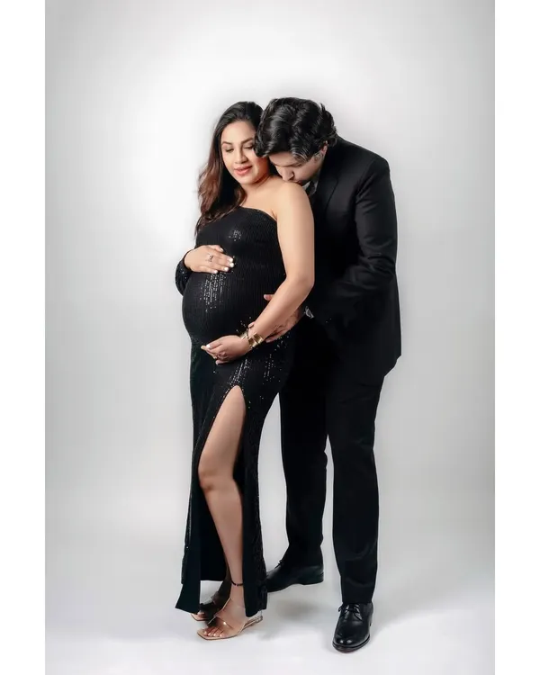 An intimate moment between an expecting couple during their studio maternity shoot. The partner’s gentle kiss on her shoulder speaks volumes of their love and shared anticipation.