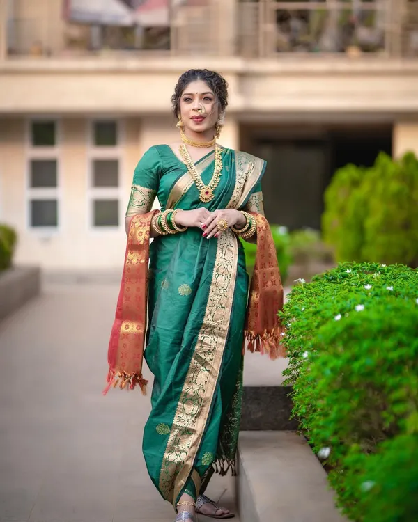 A classic green Nauvari saree, also known as a Kasta saree, is a staple for Maharashtrian brides. This full-length view shows the perfect fall of the drape and the signature pleats at the back.