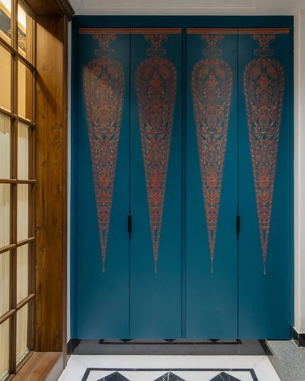 A closer look at the hand-painted shutters of the foyer shoe cabinet. Each motif is inspired by Indian miniature art, meticulously painted by artisans to create a functional piece that doubles as a stunning work of art, setting a tone of bespoke elegance from the moment you enter.