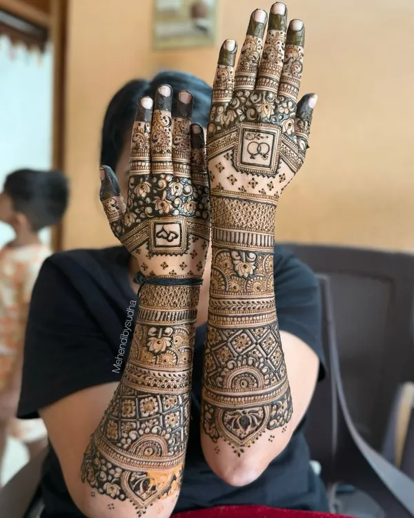 This is a classic full-arm bridal mehendi design, perfect for an engagement or wedding. Notice the fine line work, the balance between the intricate jaal (net) patterns on the palm and the bold floral bands on the forearm, creating a rich and complete look.