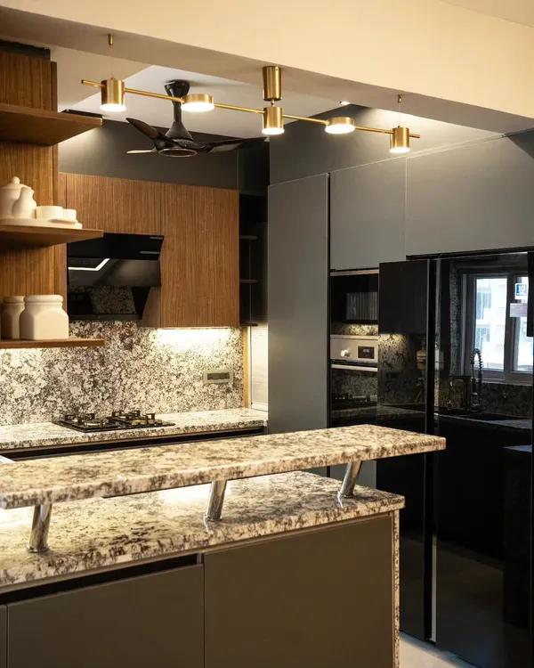 This open-plan kitchen features a multi-level island with a granite countertop that doubles as a breakfast bar. We used a combination of dark grey and wood-finish cabinets, complemented by modern track lighting, to create a sophisticated and inviting culinary space.