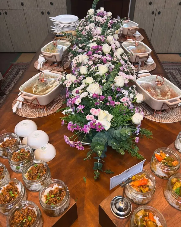 A full view of an elegant buffet table we set up for an intimate gathering. The spread includes our signature jar salads, multiple main courses in beautiful ceramic dishes, and a stunning floral centerpiece.