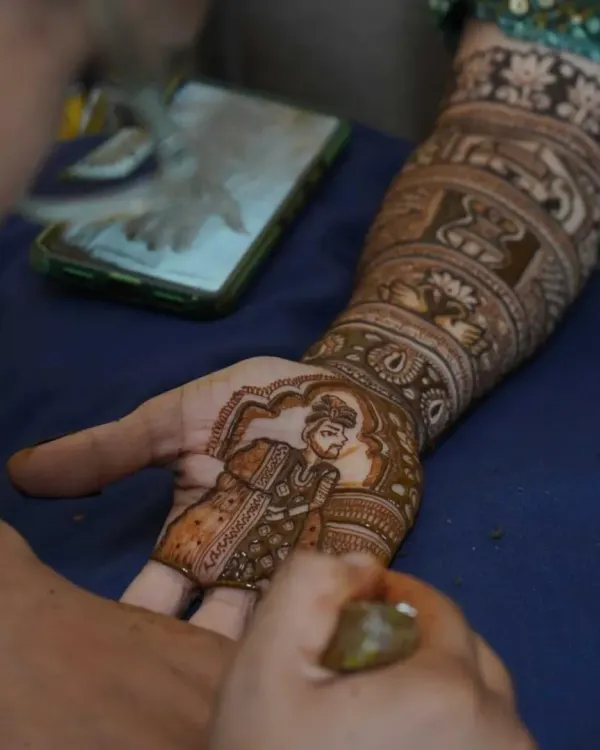 A candid moment of me creating a groom portrait for a bridal mehndi. I use a phone for reference to get the details just right.