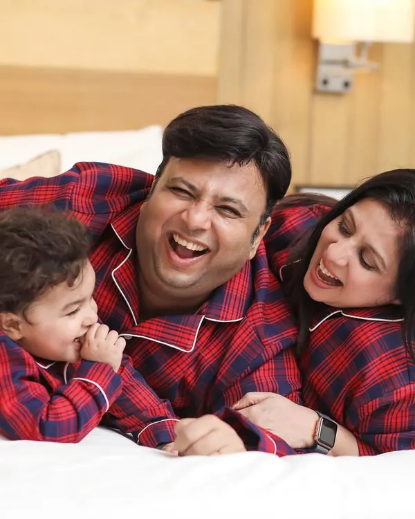 A candid moment of pure joy during a lifestyle family session at home. We love capturing these unscripted laughs, especially in fun, matching red and blue plaid family pajamas.