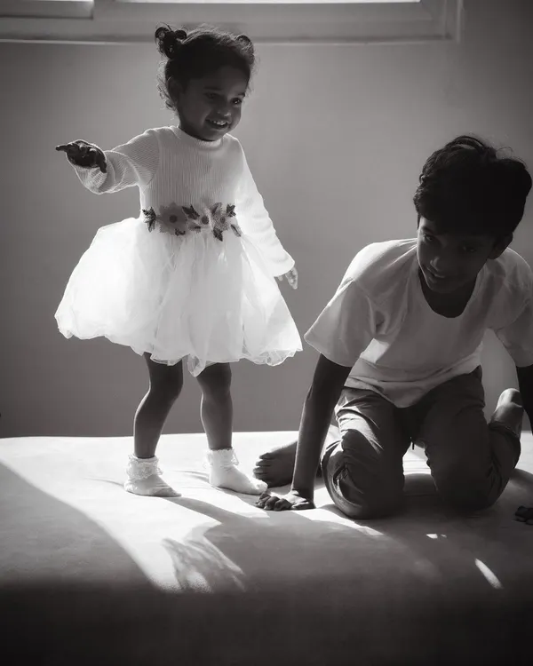 I love capturing the pure, uninhibited joy of childhood. This black and white photograph shows a young girl mid-jump on the sofa, a moment of pure energy and happiness during a natural family moments photography session at her home in Bangalore.