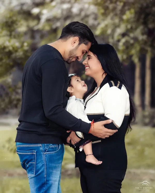 A beautiful, intimate family portrait taken outdoors. The focus is on the loving gaze between the parents and their baby, creating a timeless image of connection.
