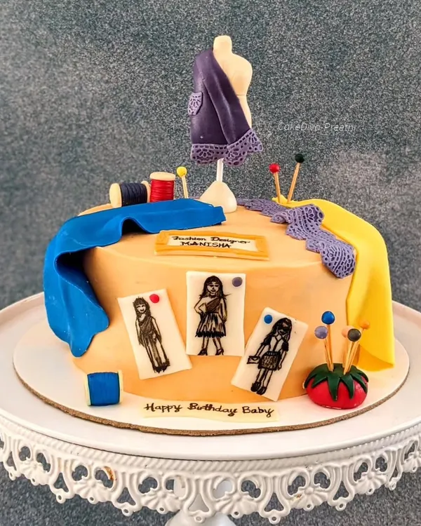 My first cake for a fashion designer! The design features a mannequin, bolts of fabric, and hand-drawn fashion sketches (croquis) on fondant, all edible.
