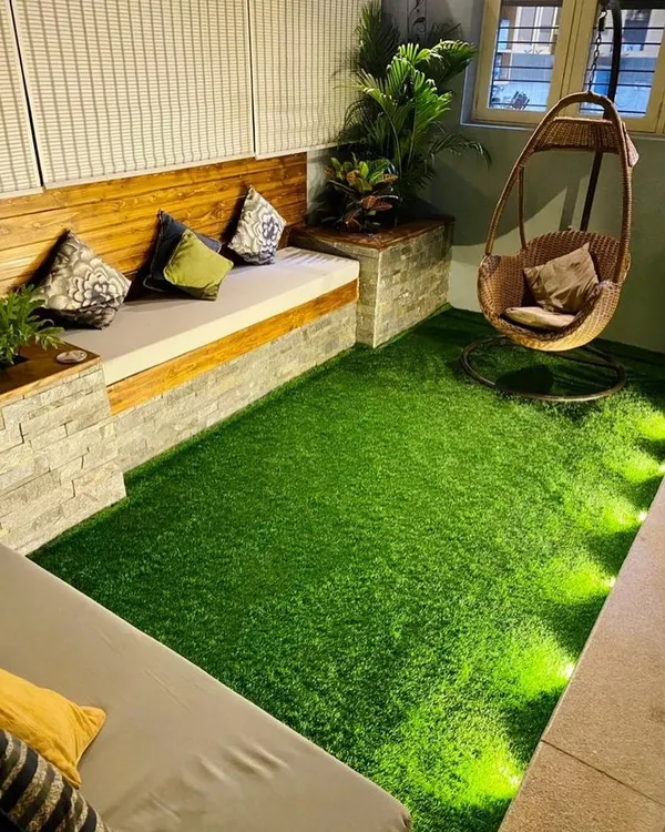 We transformed this area into a lush indoor garden, complete with soft artificial grass, integrated floor lighting, and custom-built seating with stone cladding. The wicker swing chair creates a perfect nook for relaxation, truly bringing the outdoors inside.