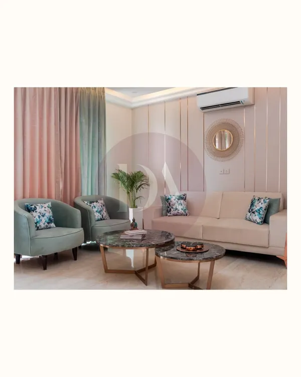 This living room showcases several custom pieces, including the pastel green armchairs and the nested marble-top coffee tables. Every piece is designed to complement the overall aesthetic of comfortable luxury.