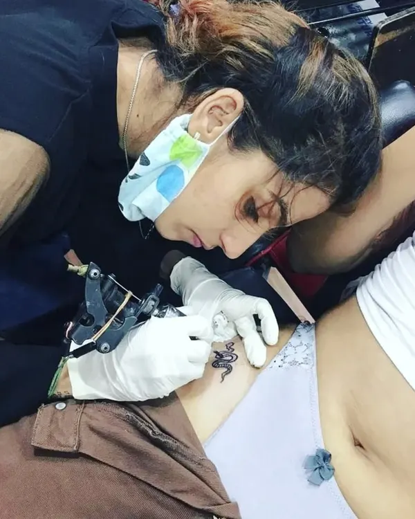 You learn by doing. This image shows a student getting practical experience, carefully tattooing a client in my studio. This is the core of my teaching method.