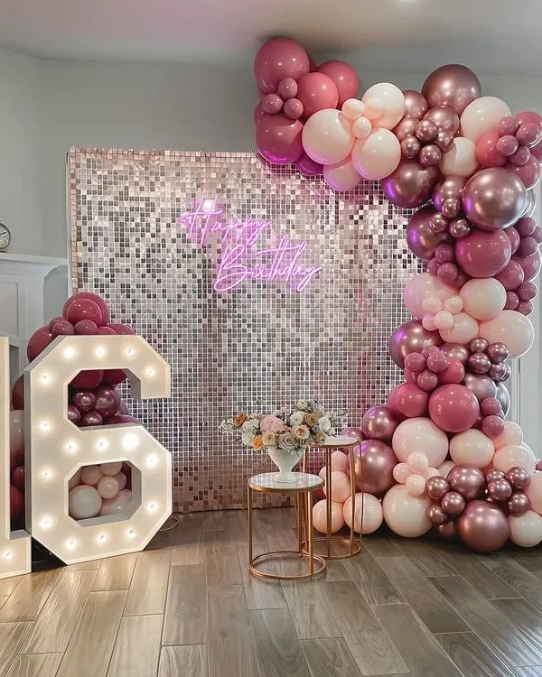 Turning 16 is a huge milestone. For this sweet sixteen party, I designed a glamorous photo wall with a silver sequin backdrop, a custom neon sign, and a cascade of pink and metallic balloons.