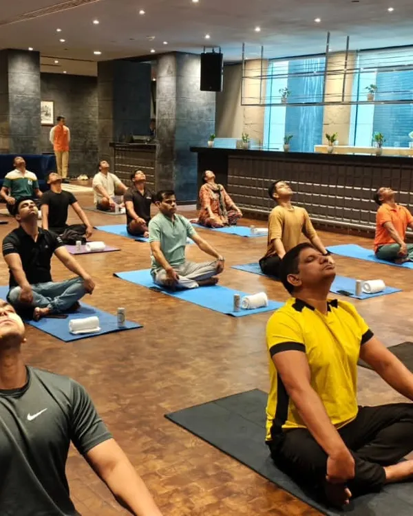 A corporate yoga session in progress, with employees practicing neck stretches to relieve tension from long hours at the desk. These simple movements can make a huge difference in preventing chronic pain and improving posture.