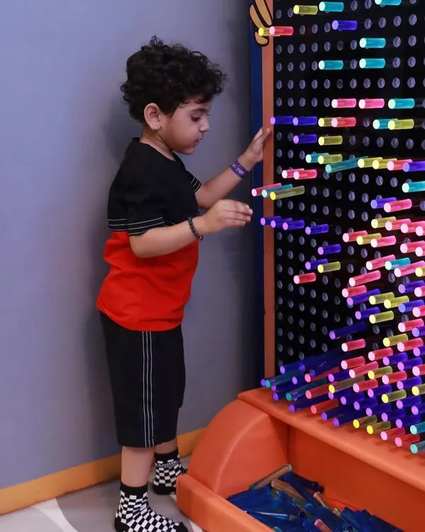 A young boy creating patterns on our interactive light wall. This giant pegboard is a fantastic tool for creativity, color recognition, and fine motor skills.
