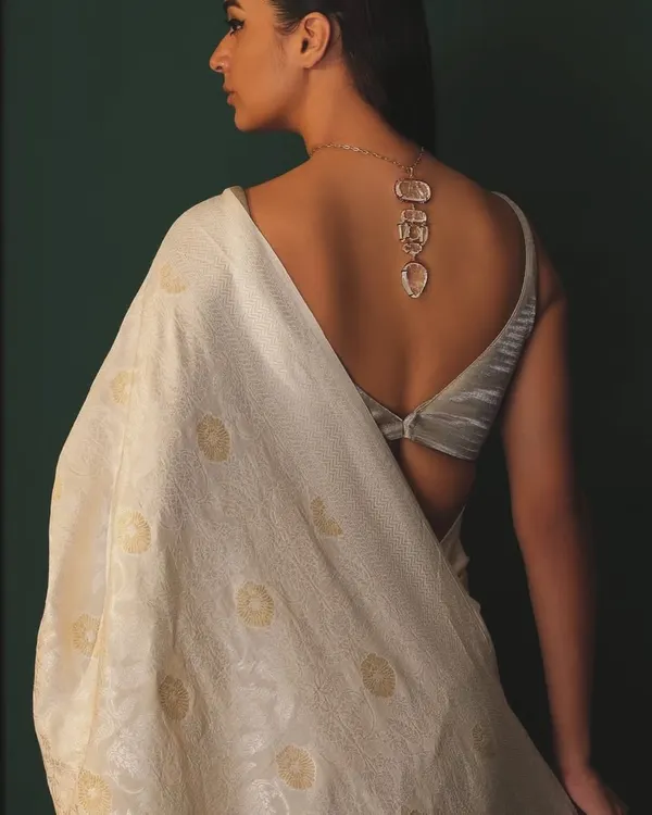 The back of a saree look is just as important as the front. Here, a stunning carved necklace by Hanut Singh is styled as a back accessory, adding a surprising and artistic element to this elegant white saree.