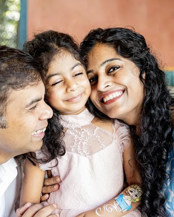 A happy squeeze from mum and dad. This candid family photo from a birthday party is full of genuine smiles and affection. It's these in-between moments that often become the most cherished memories.