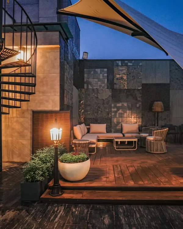 The terrace at our Vikaspuri project, featuring a spiral staircase, a custom stone-paneled wall, and a comfortable outdoor lounge area perfect for evenings.