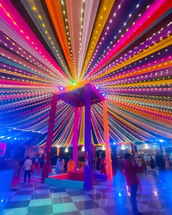 A stunning night view of a multi-colored canopy illuminated with thousands of fairy lights. This creates a magical, starry effect for a Sangeet or reception party.