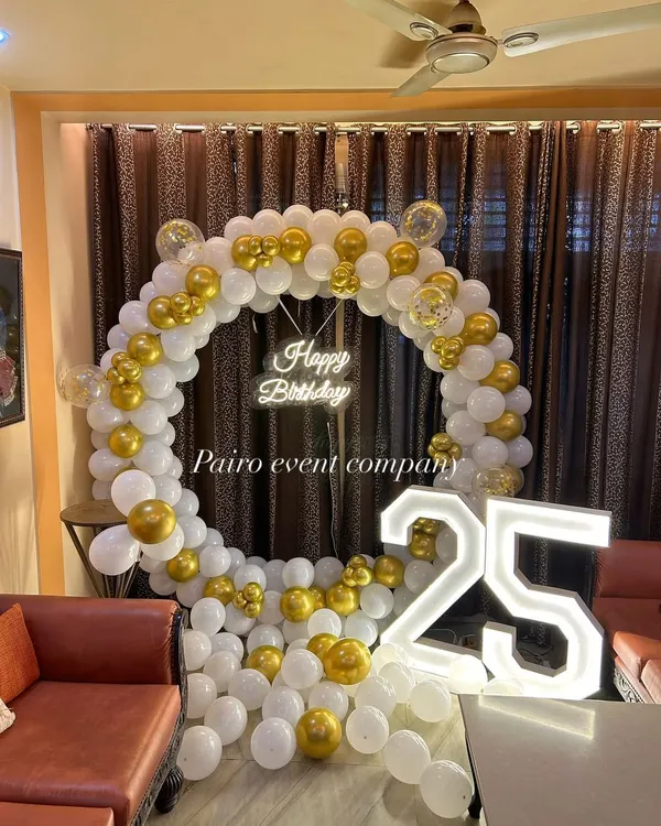 A classic white and gold balloon ring with a 'Happy Birthday' neon sign and '25' marquee numbers, perfect for a milestone celebration at home.
