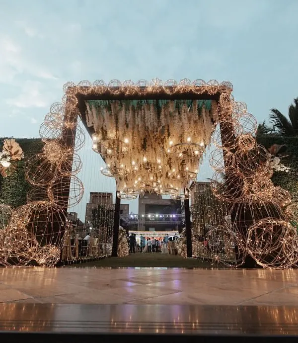 This entrance was designed to be a spectacle of light and texture. I used intricate wire-frame spheres wrapped in fairy lights and a ceiling of hanging white florals to create a magical, immersive experience.