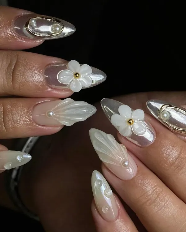 An intricate set featuring 3D sculpted shells, pearls, and transparent floral elements. This level of detailed work is what we practice in the advanced nail art course.