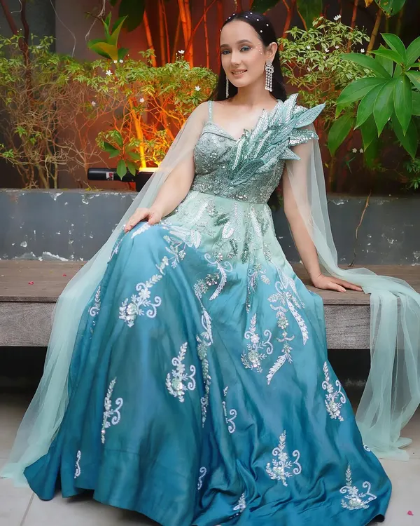 Feel like a character from a fairytale in this stunning ombre gown. The color fades from sea green to deep blue, adorned with silver embroidery and a flowing cape for a touch of magic.