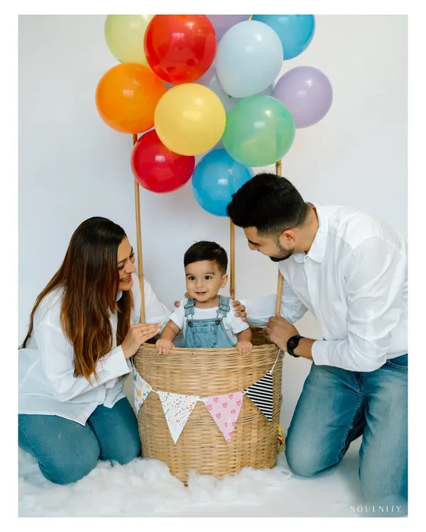 A first birthday is a celebration for the whole family. Including parents in the hot air balloon setup creates a beautiful portrait of shared joy and adventure on this special day.