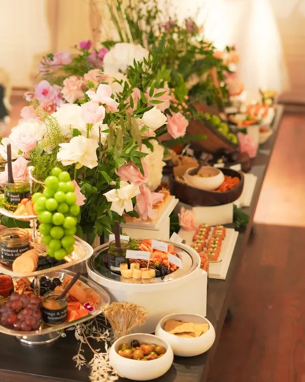 A closer look at our magnificent grazing table, showcasing tiers of fresh Kumaoni grapes, artisanal cheese platters, and an array of delicate canapés. The composition is designed to invite guests to explore a variety of flavors and textures.