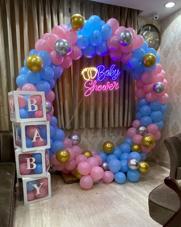 A beautiful baby shower setup I did, featuring a full circular balloon arch in pink, blue, and gold. The glowing 'Baby Shower' neon sign and transparent 'BABY' blocks filled with matching balloons create a perfect photo backdrop for celebrating the parents to be.