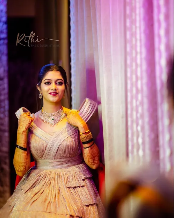 Our gorgeous bride ready for her cocktail party in a custom shimmered rose gold gown. The design features a tiered skirt and unique sculpted shoulders for a modern, glamorous look.