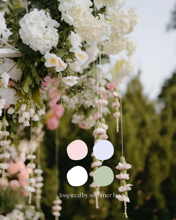 Inspired by summer hues, this image shows how I draw color palettes from nature itself. The hanging floral strings and lush white arrangements create a soft, romantic feel for an outdoor event.