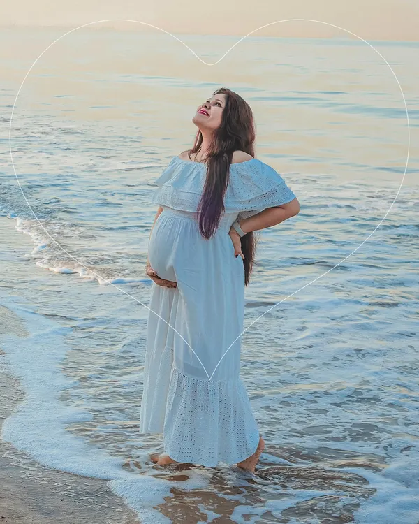 A serene solo portrait of a mom-to-be standing in the gentle ocean surf. The natural setting adds a sense of calm and wonder to this outdoor maternity photo.