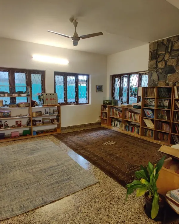 An overview of our elementary classroom. The space is open and uncluttered, with materials organized on low shelves, inviting children to choose their own work. The stone wall and wooden furniture bring the texture of the natural world indoors.